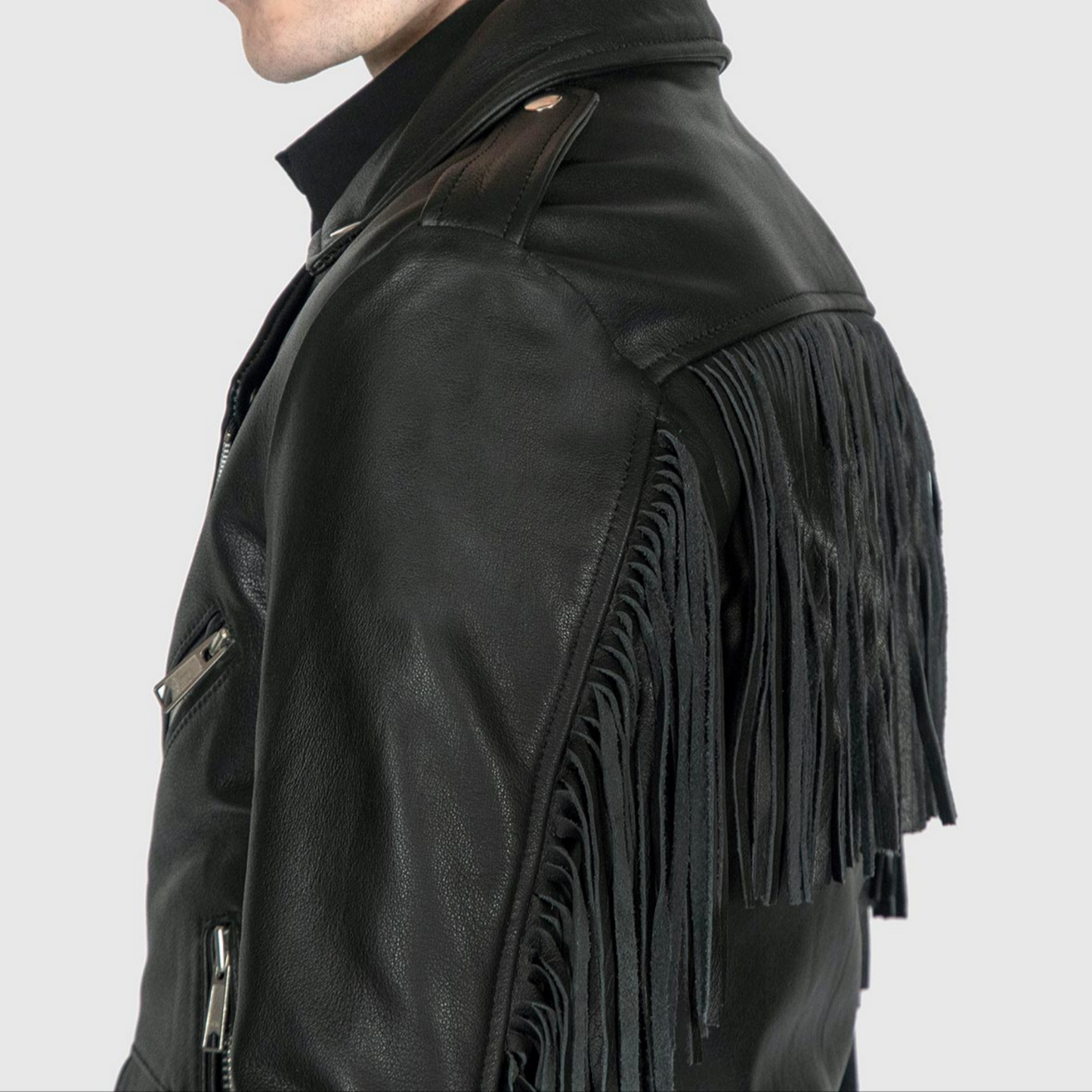 Close-up of black leather biker jacket showing fringe detail, belt, and premium stitching