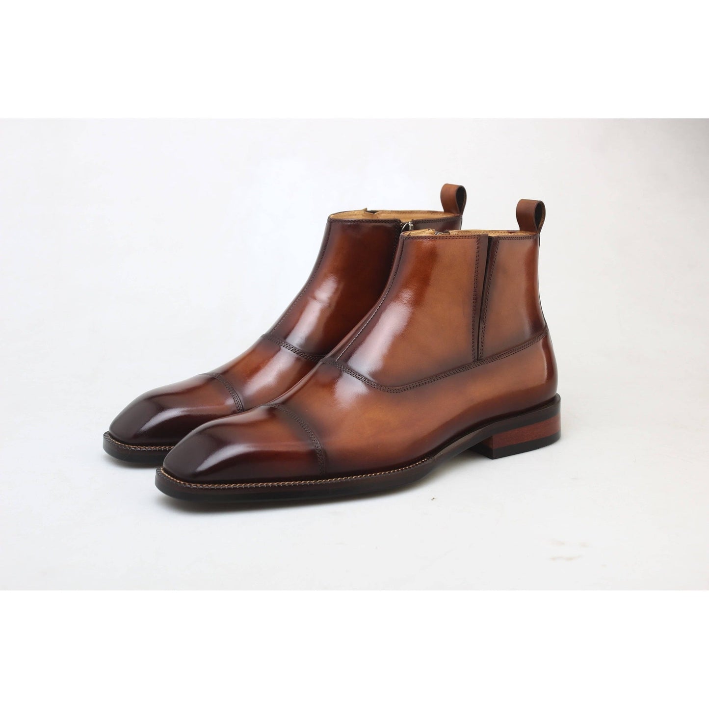 Close-up of handcrafted brown leather ankle boots placed on autumn leaves – premium men’s footwear with rich patina.