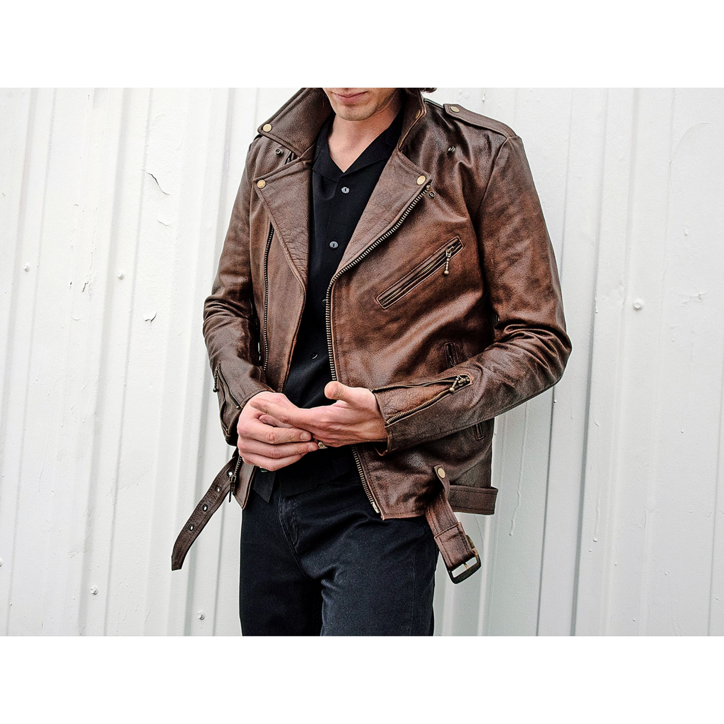 Front view of model wearing men's vintage brown slim fit motorcycle leather jacket with belted waist and classic biker style