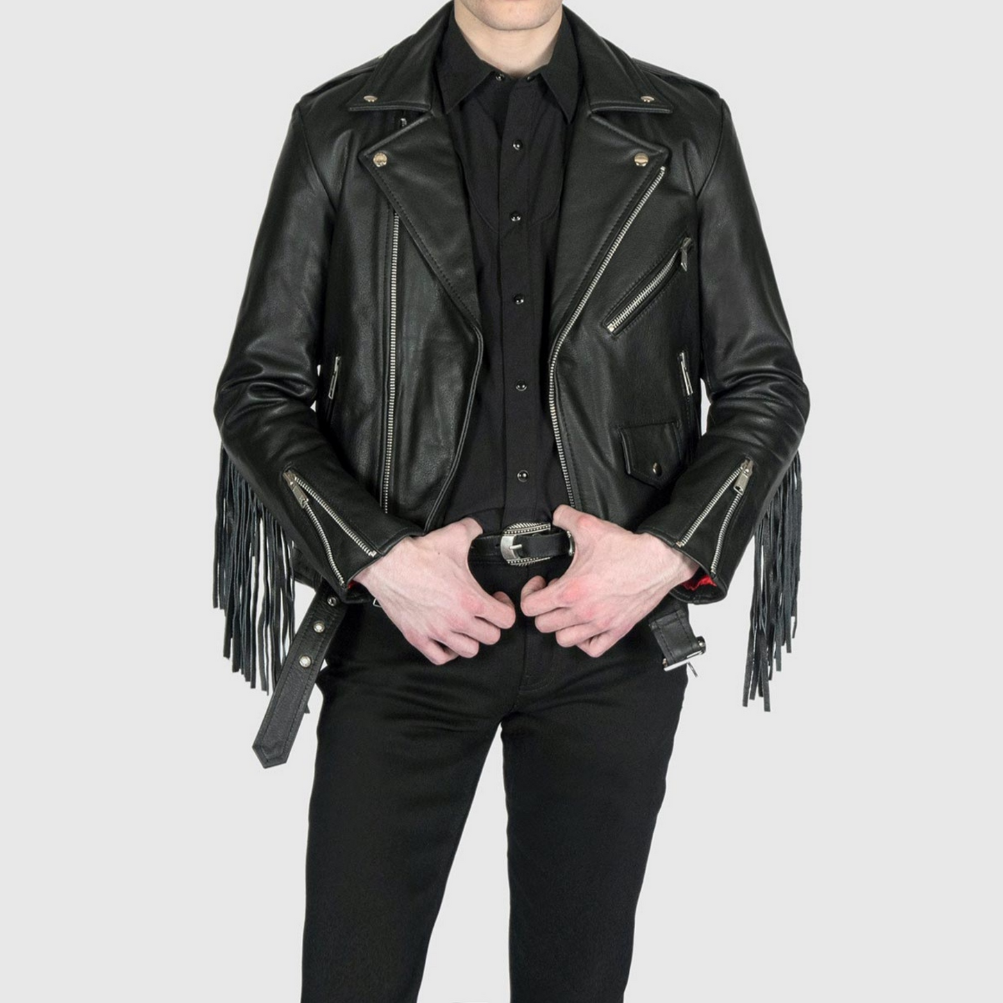 Full view of model wearing men's black fringed slim fit motorcycle biker leather jacket with belted waist and fringe detailing on arms and back
