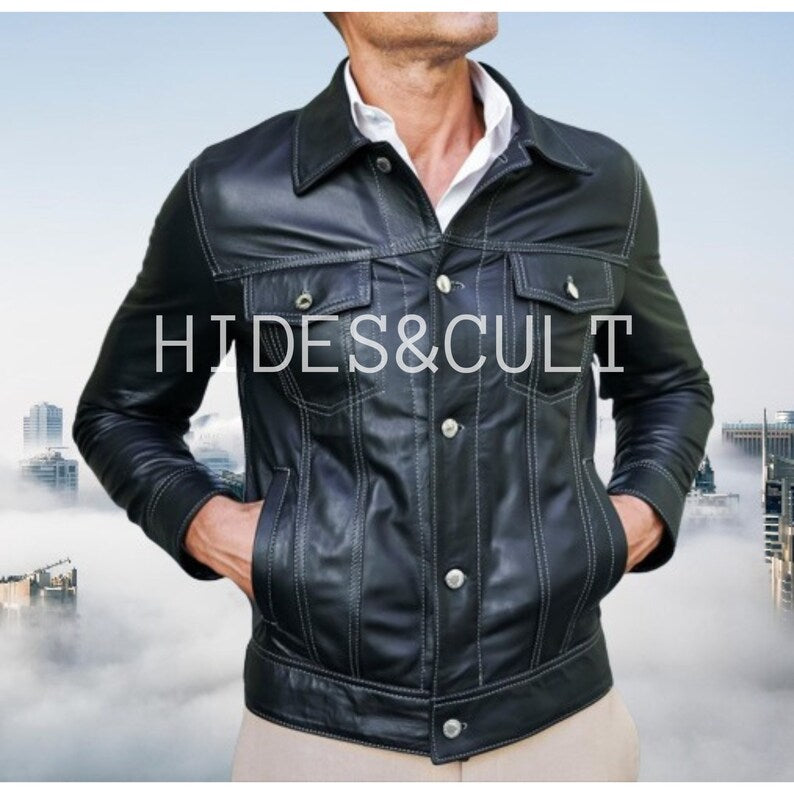 Men's classic black genuine leather trucker jacket from Hides & Cult, featuring white contrast stitching. Model with hands in pockets, showcasing fit and texture.