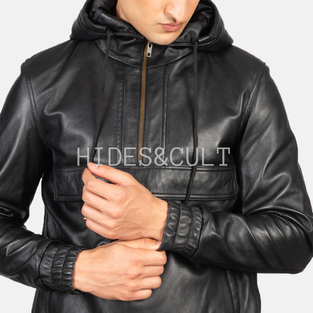 Close-up of male model adjusting the zipper of a black genuine leather hoodie jacket by Hides & Cult with detailed stitching and drawstrings.