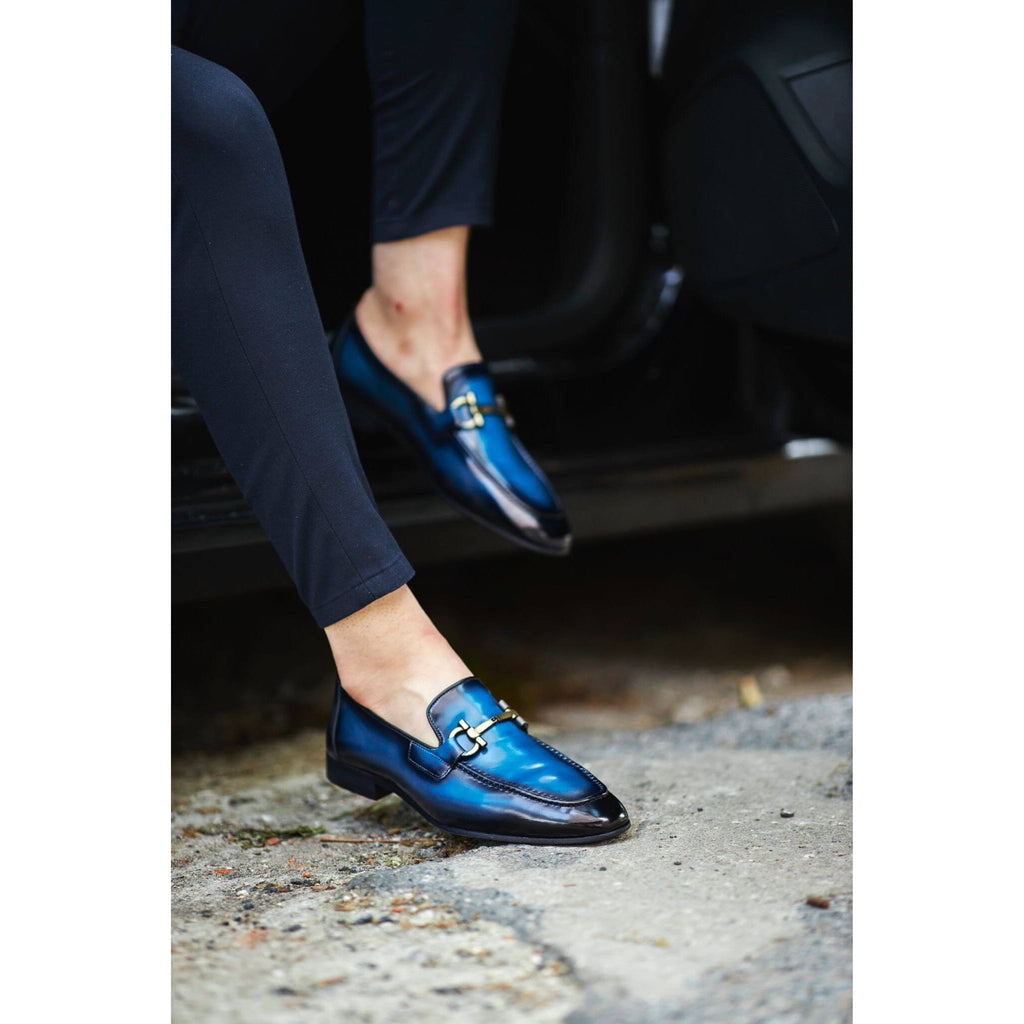 Stylish men's blue PATINA leather loafers with metal bit detail, paired with black pants, captured while stepping out of a car – luxury footwear for modern gentlemen.