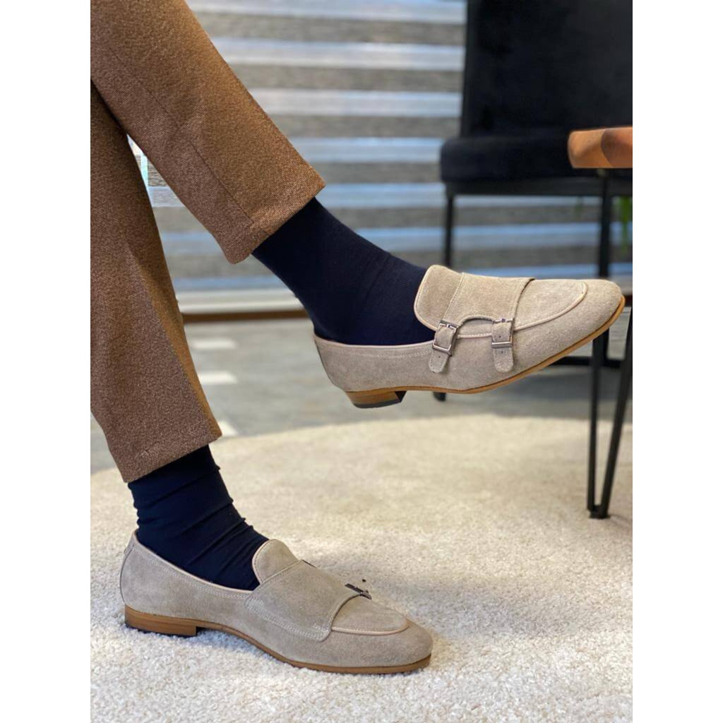 TOp View of a man wearing beige suede double monk strap loafers with navy socks and brown textured trousers, standing near a marble step.